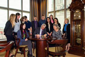 Marquette University president Michael Lovell, Ph.D., signs the Catholic Climate Covenant's Saint Francis Pledge surrounded by student and faculty supporters.